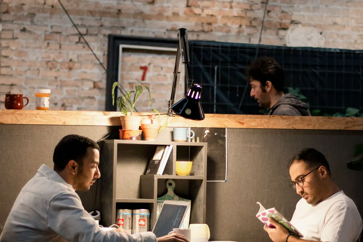 Two people talking across a table in a warmly lit brick-walled workspace