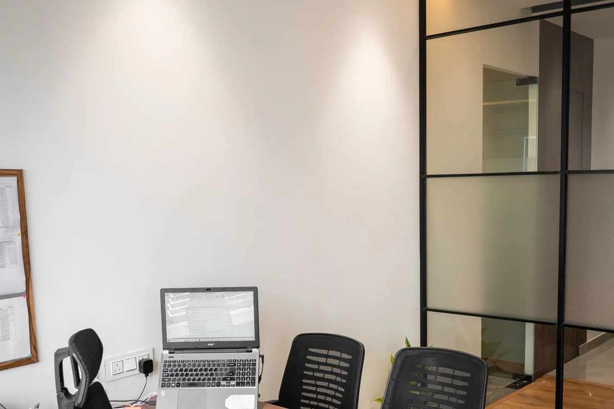 Small private office with a desk, task chair, and glass partition