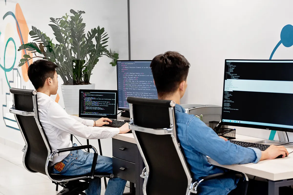Two colleagues working side by side at desks in an office