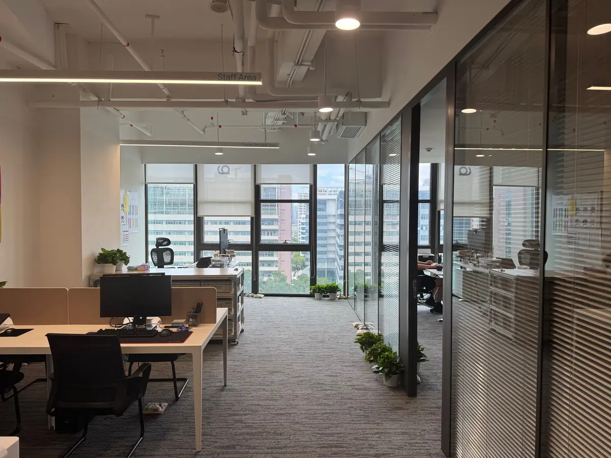 Open-plan office with glass partitions, empty desks, and a city view