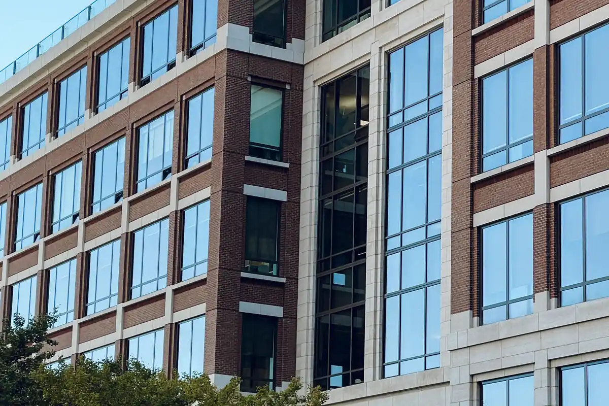 Mid-rise brick and glass office building above a tree-lined street