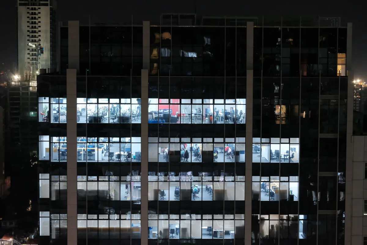 Office tower at night with many floors of lit windows