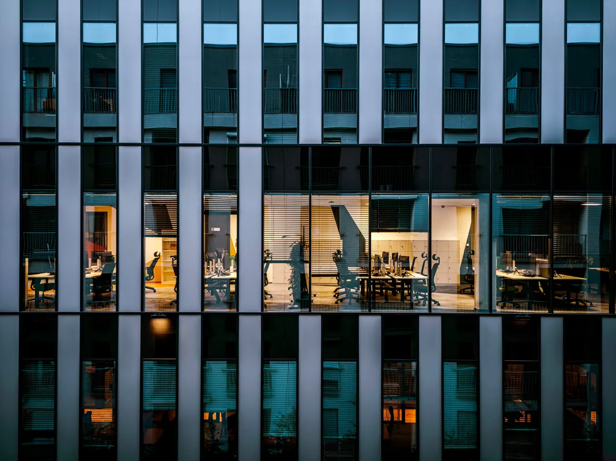 Modern office building facade, a grid of glass with a few lit interiors