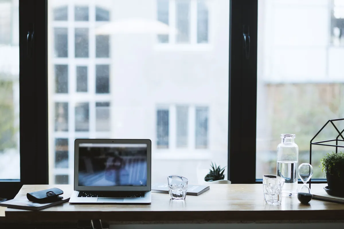 Laptop on a clear desk in front of a large window